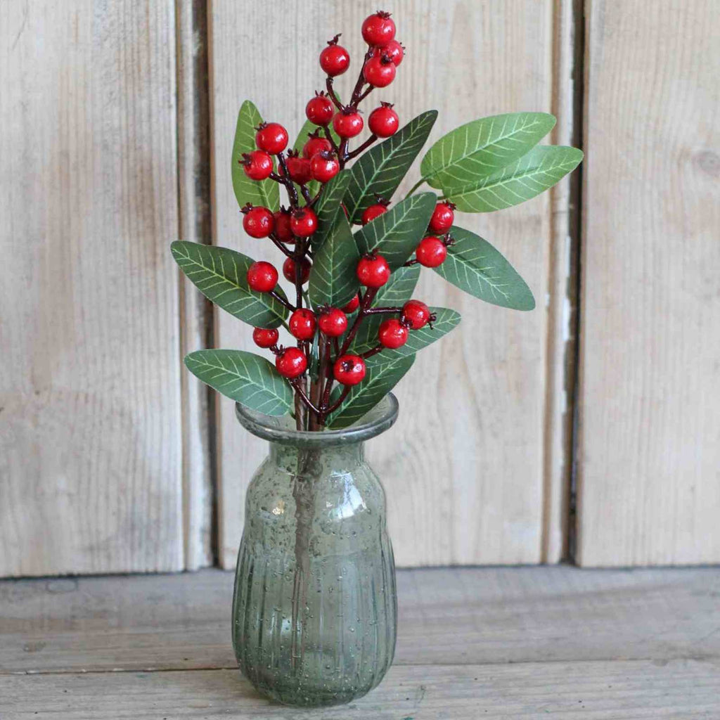 artificial red berry stems in green glass vase